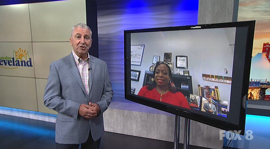 Adult man in studio next to screen with adult woman on video call.