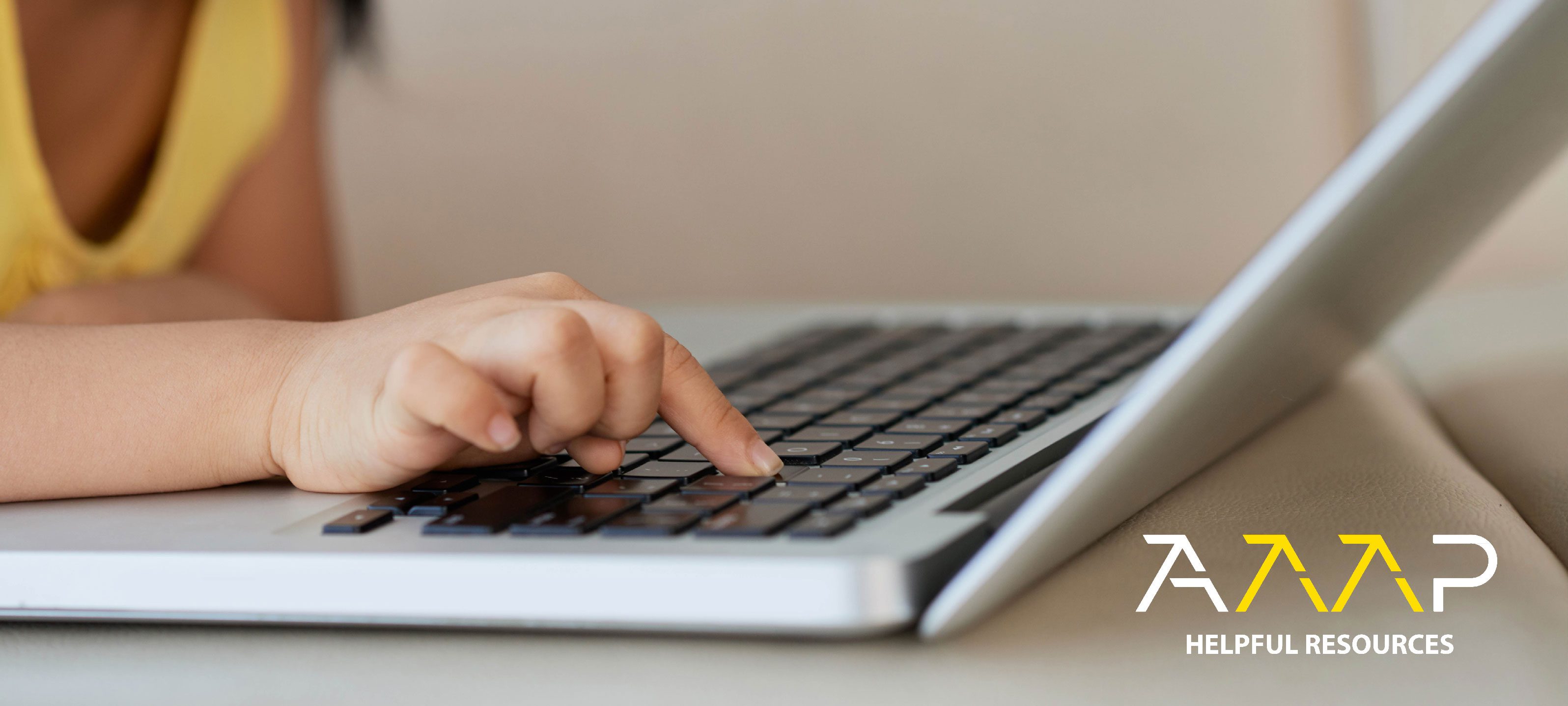 Child's hand typing on a laptop keyboard.