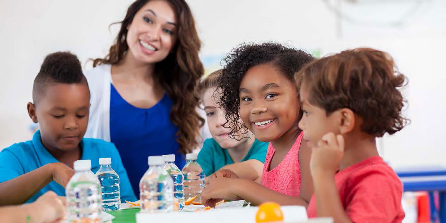 Adult and children at a table with water bottles and orange peels.