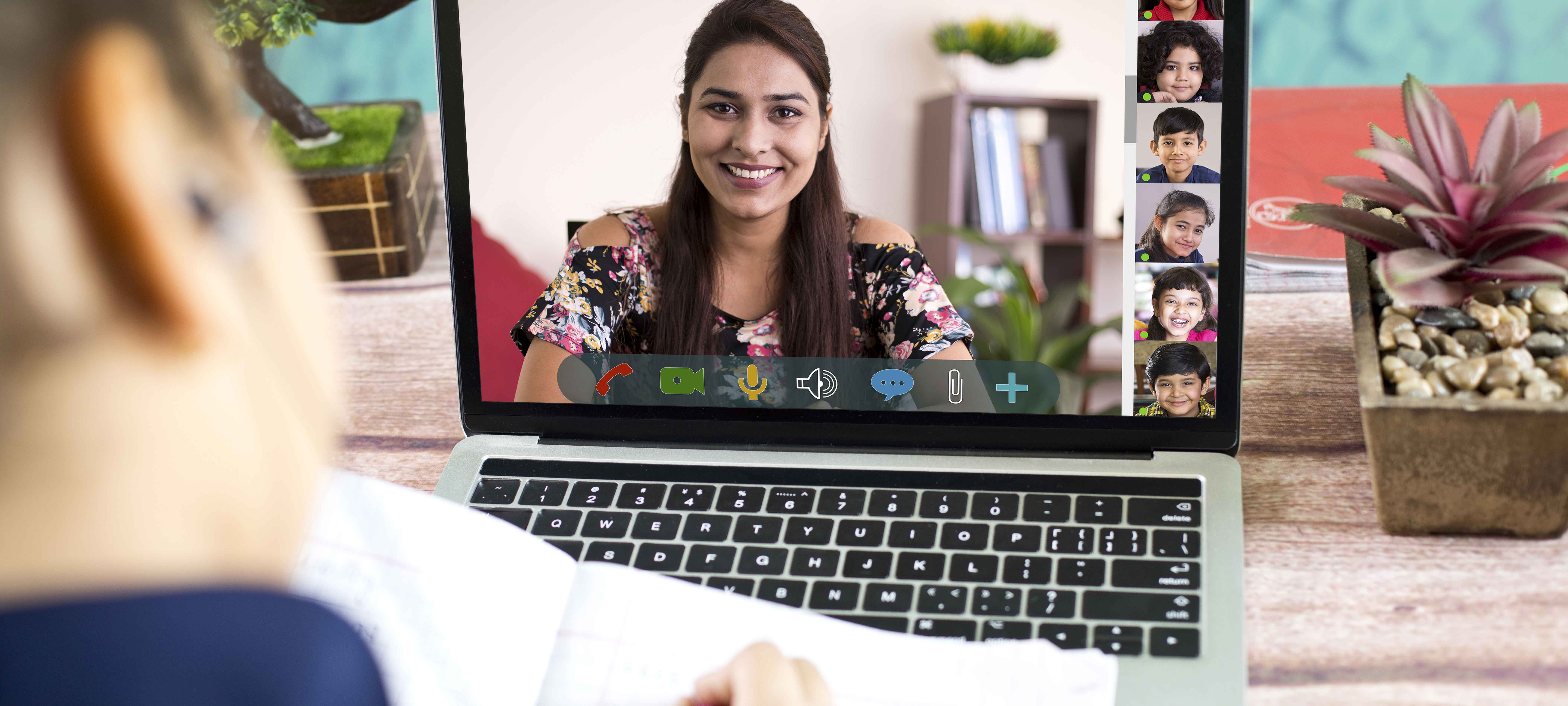 Adult on laptop video call with other adults and children.