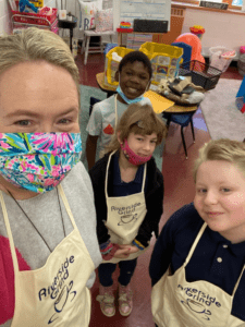 Adult and three children in aprons smiling at the camera.