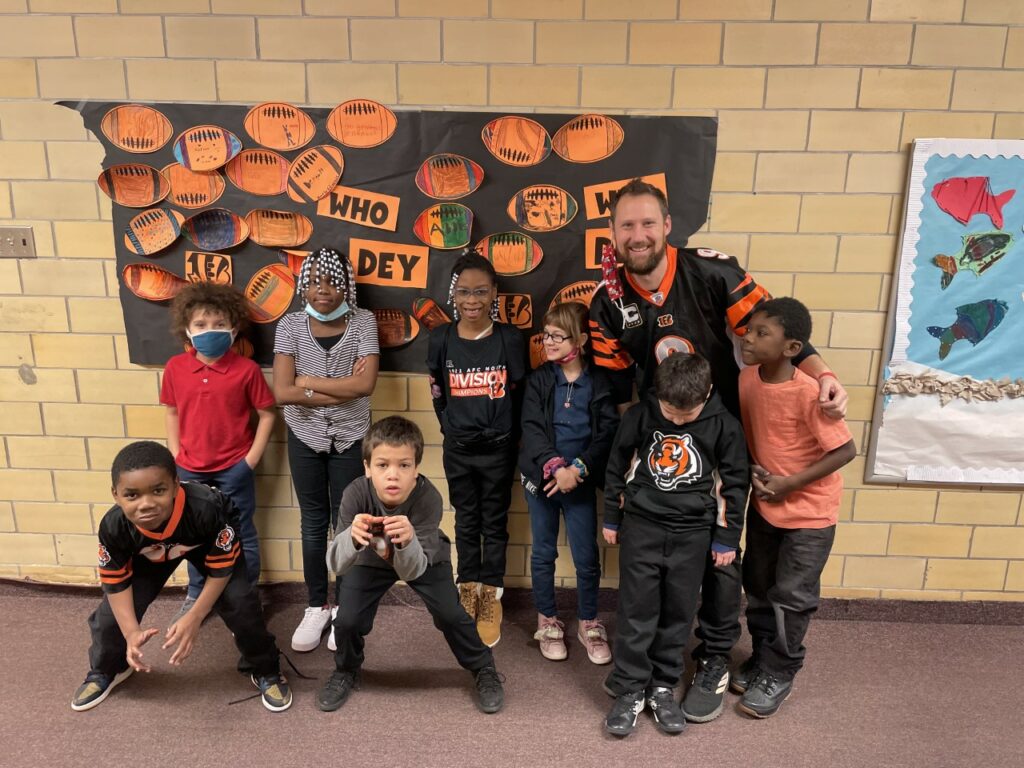 Adult and children posing in a school hallway.