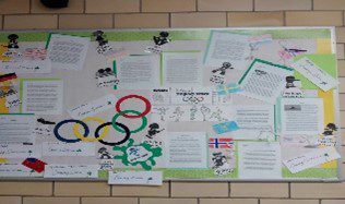Bulletin board with Olympic rings and assorted papers.
