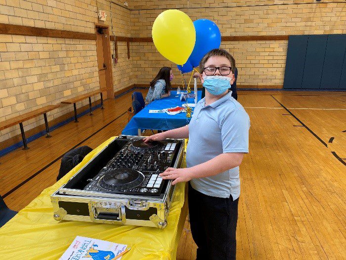 Child DJing at an event in a gymnasium.