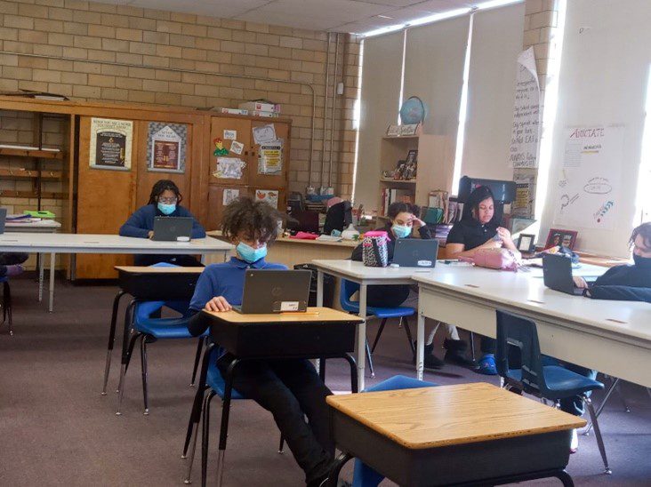 Children in a classroom using laptops at their desks.