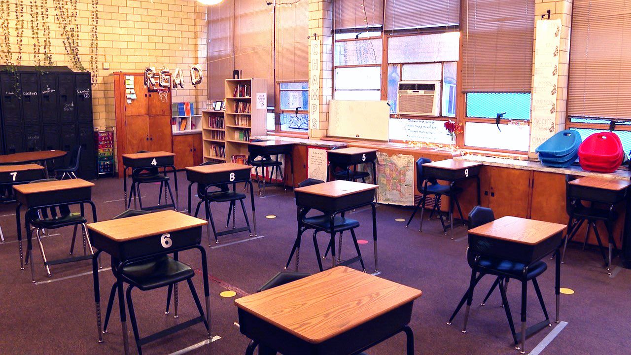 Empty classroom with desks, chairs, lockers, and bookshelves.