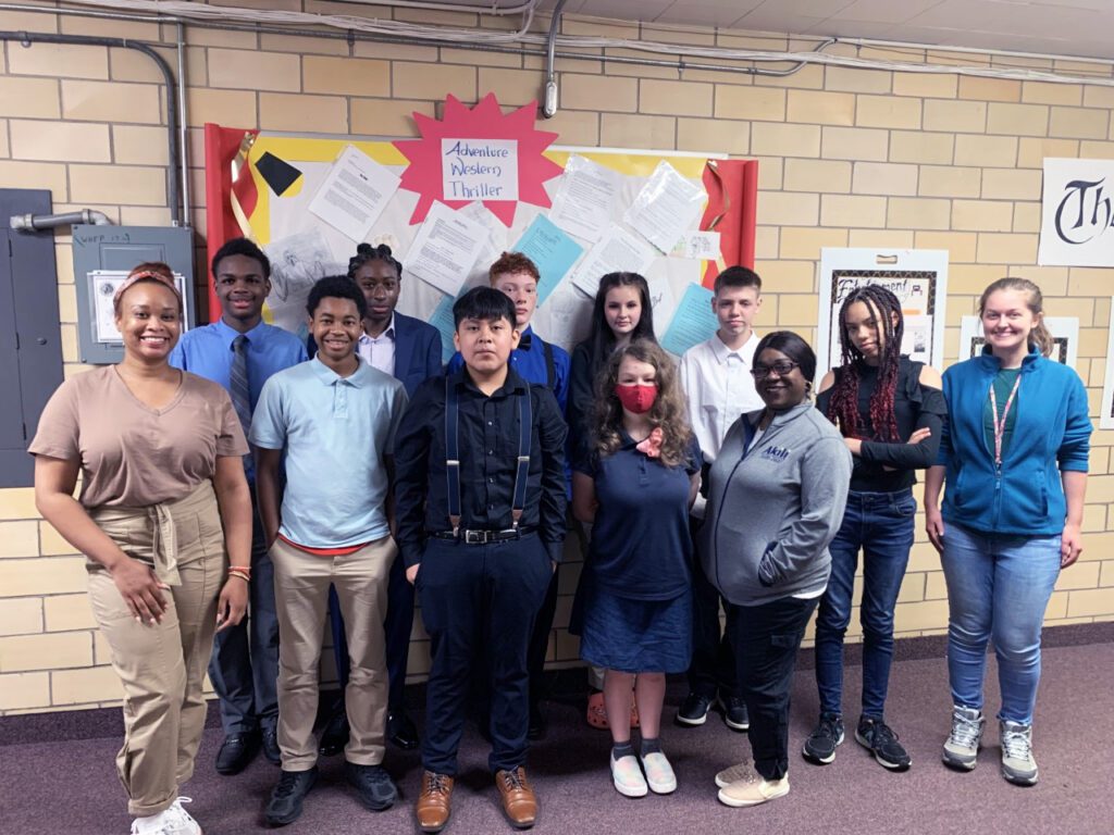 Two adults and eleven children pose in a school hallway.