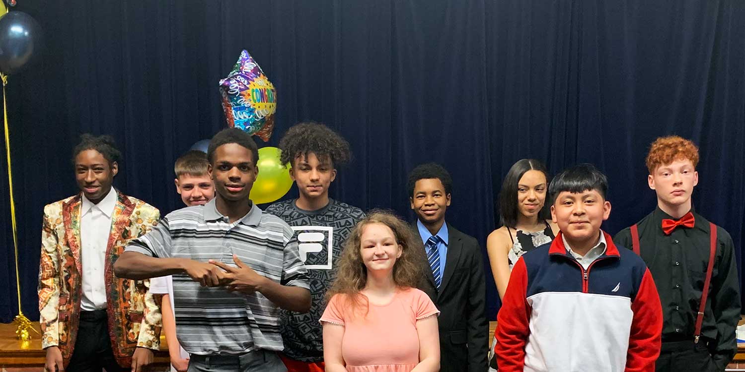 Ten children in formal attire pose for a group photo.