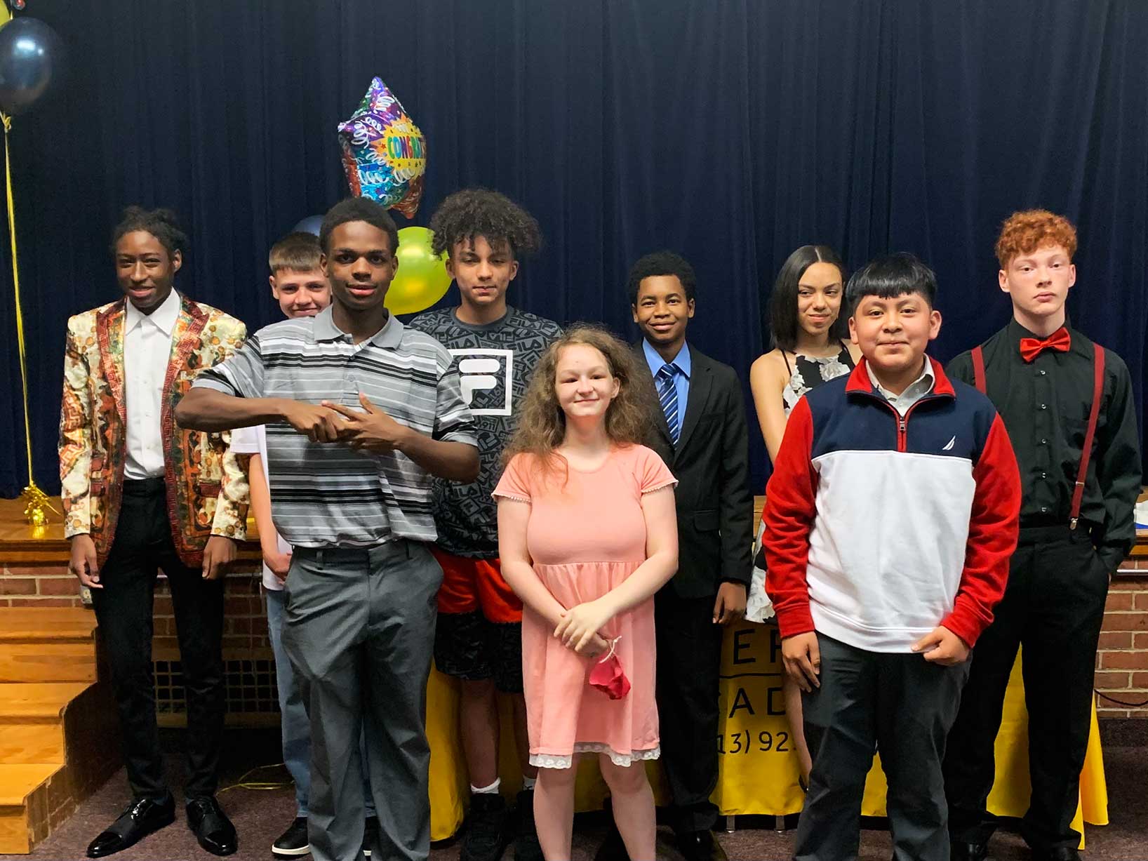 Nine children pose for a photo with balloons.