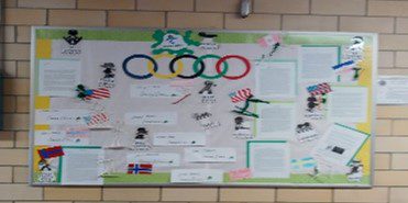 Bulletin board with Olympic rings, flags, and text documents.