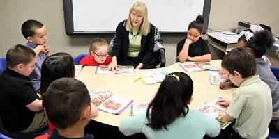 Adult and children reading books together at a table.