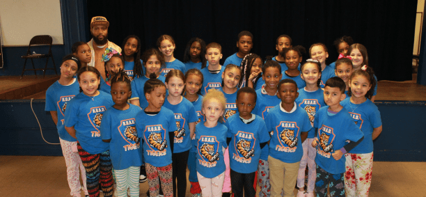 Group of children and adult in blue tiger shirts.
