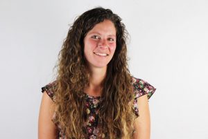 Smiling adult with long curly hair.