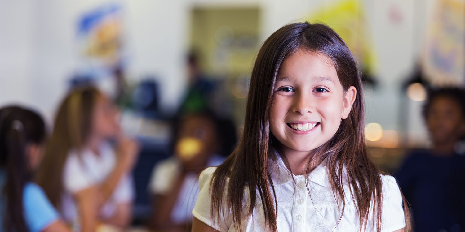 Smiling child in a classroom setting.