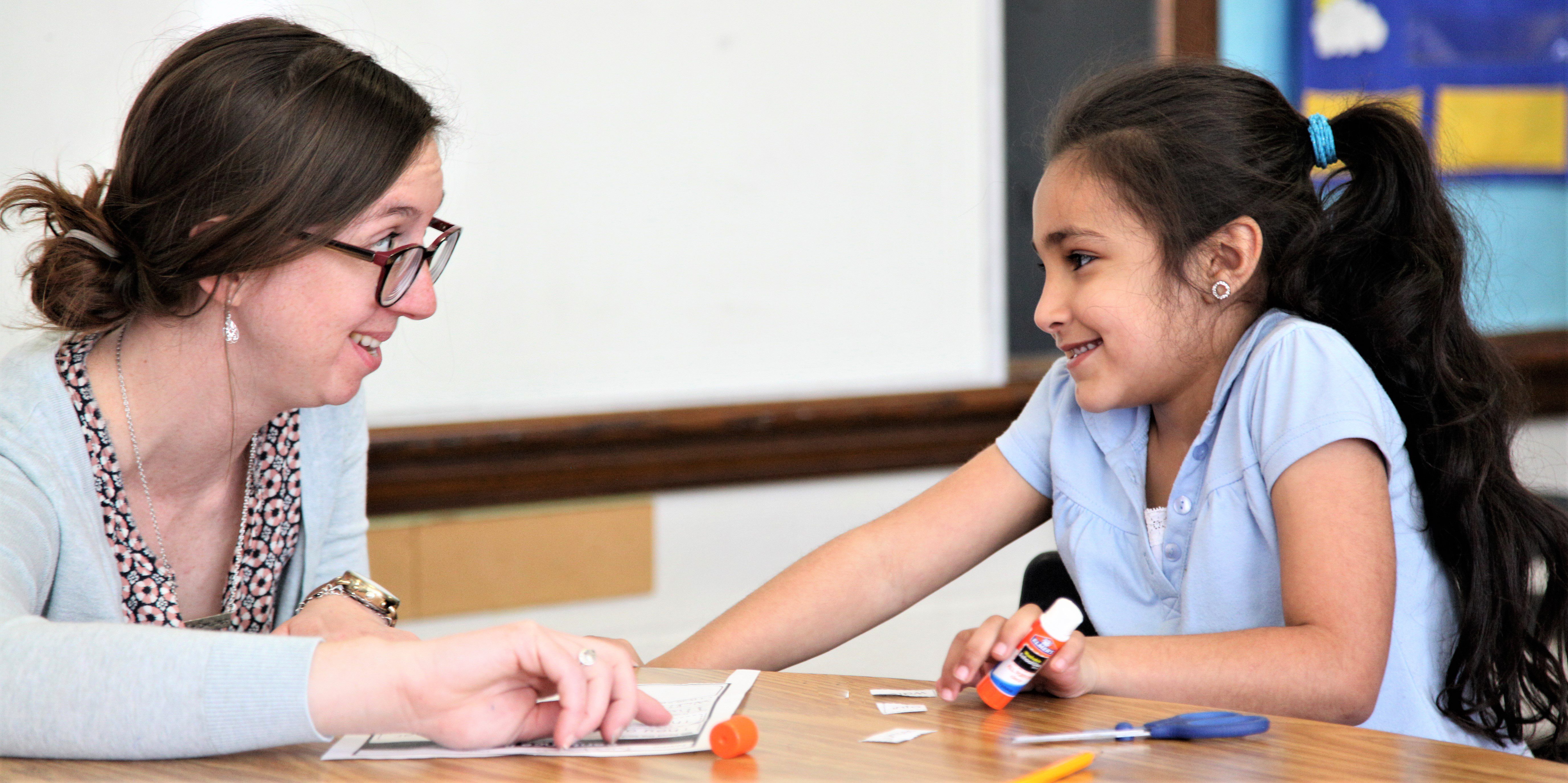 Adult and child smiling while crafting with glue.