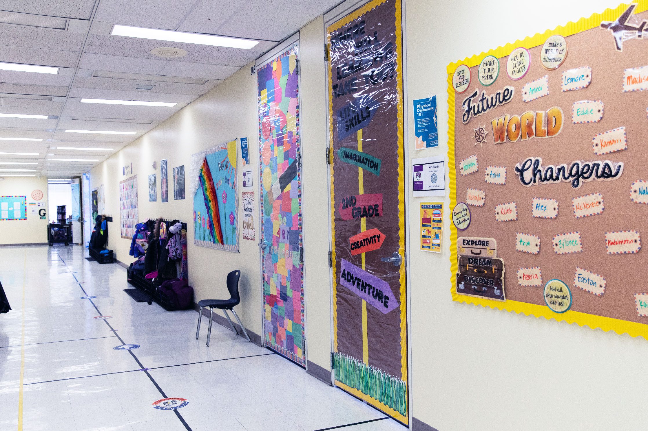 School hallway with decorated doors, bulletin board, and floor markers.