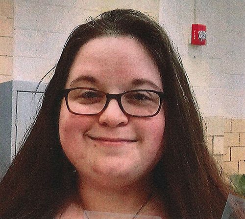 Smiling adult with glasses and long dark hair.