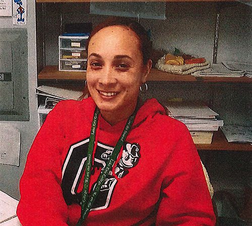 Smiling adult in red hoodie with green lanyard.