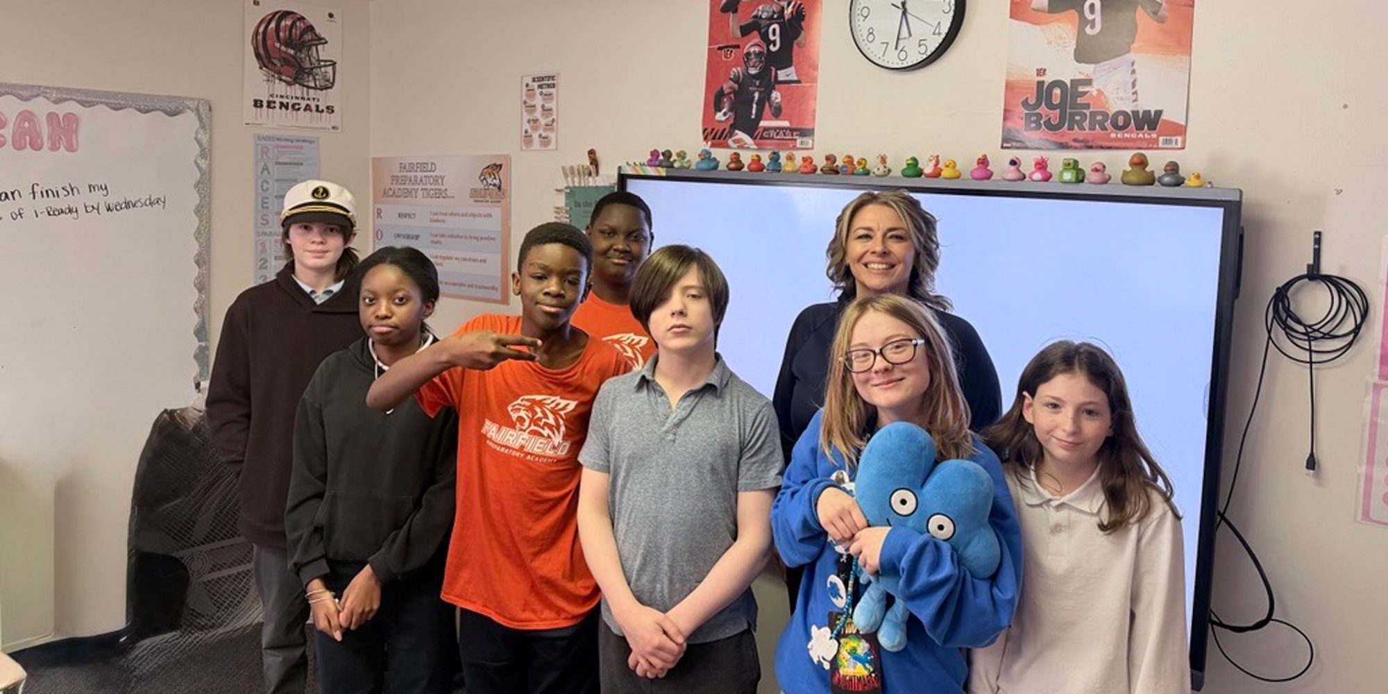 Adult and seven children smiling in a classroom.