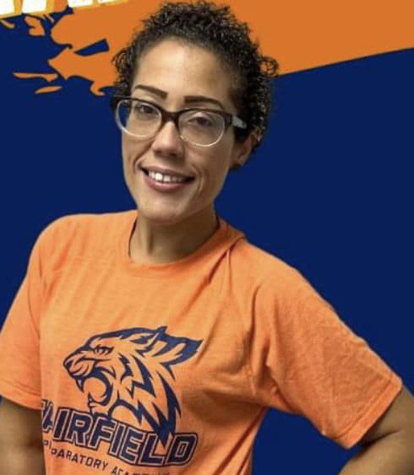 Smiling adult in orange shirt with blue tiger logo.