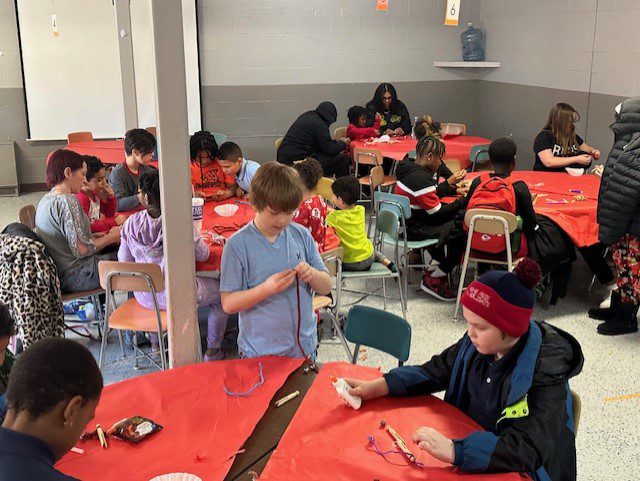 Children and adults doing crafts at tables.