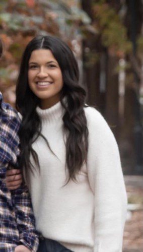 Smiling adult in white turtleneck sweater.