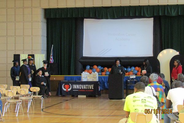 Graduation ceremony with adults on stage and screen showing "Innovative Career Academy."