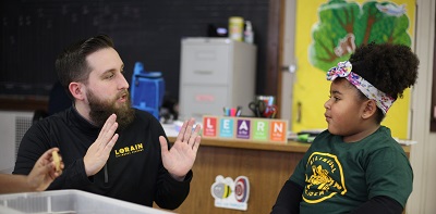 Adult and child talking at a table in a classroom.