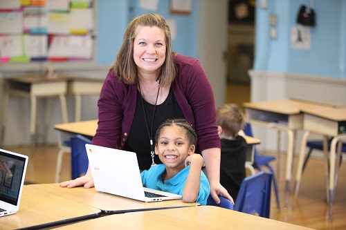 Adult and child smiling with a laptop.