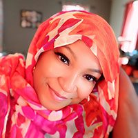 Smiling adult wearing a colorful patterned head covering.