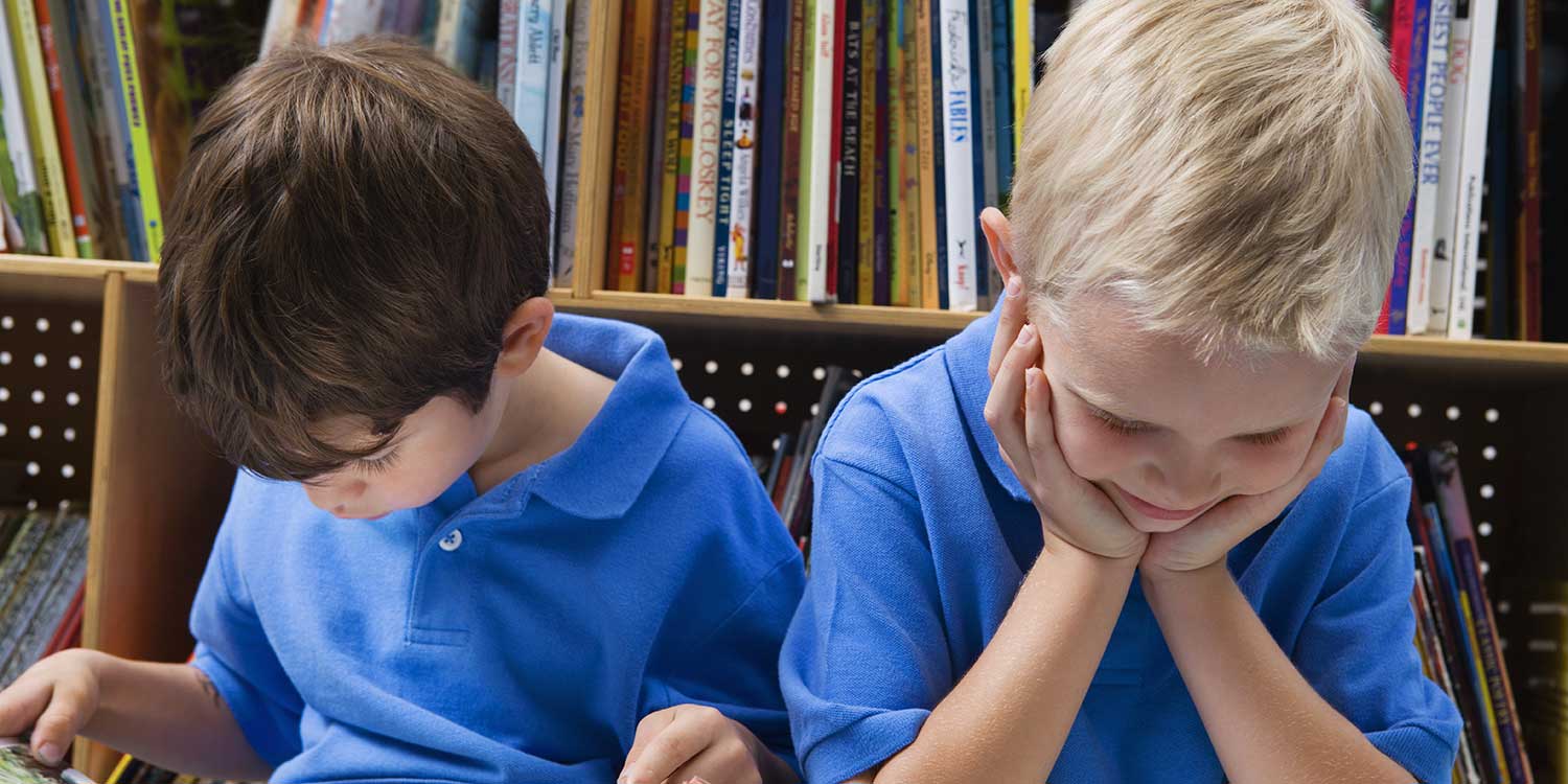 Two children in blue shirts reading books.