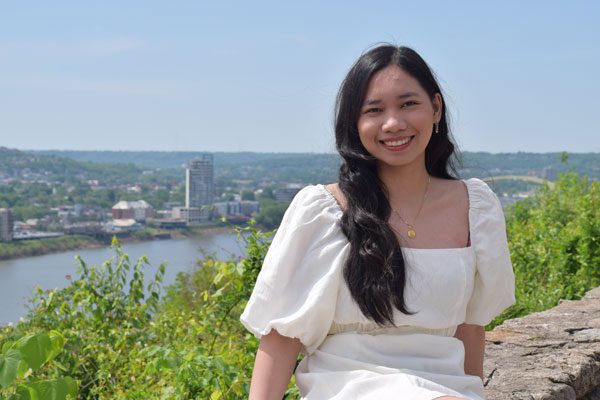 Smiling adult with city and river in background.