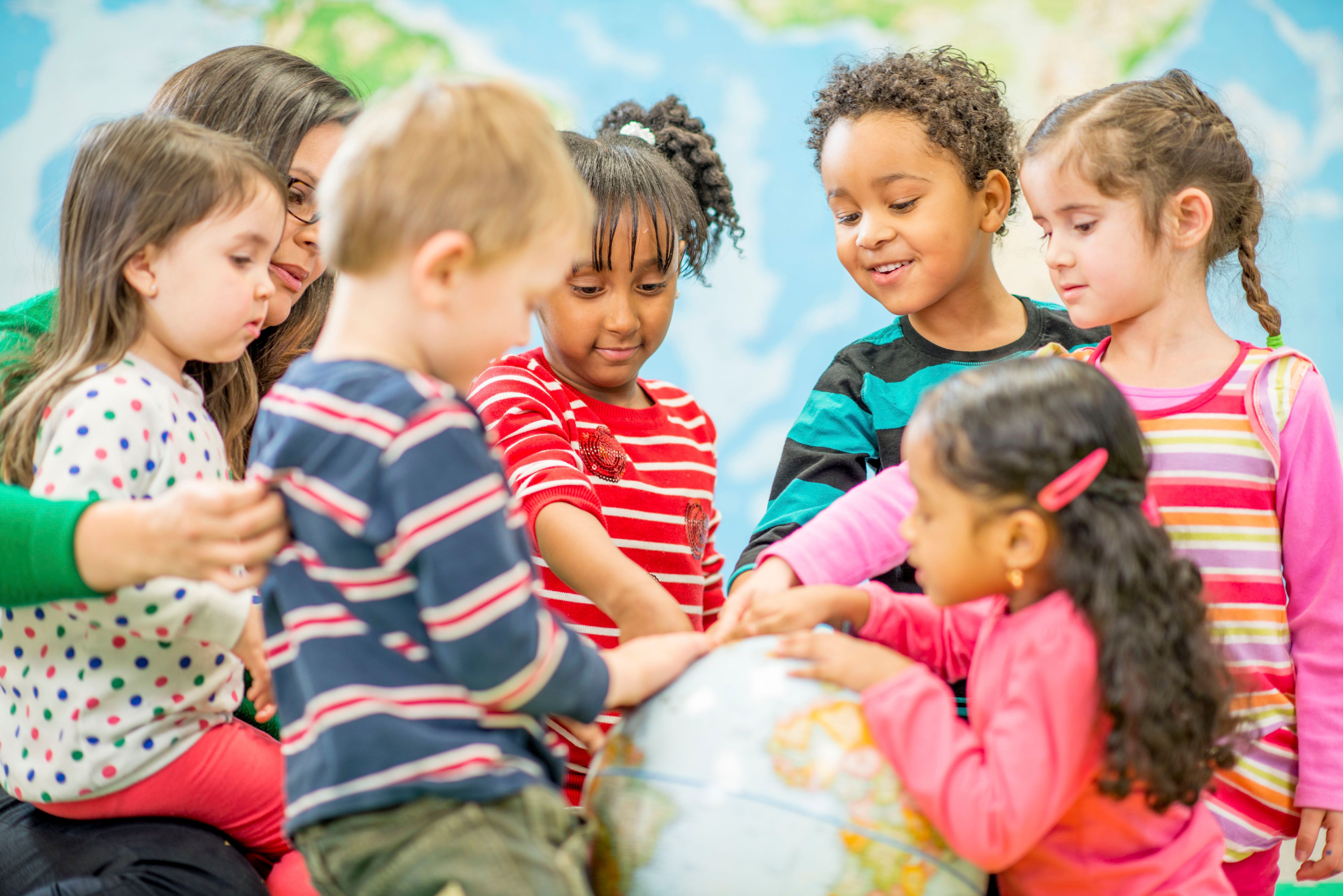 Adult and children gathered around a globe.