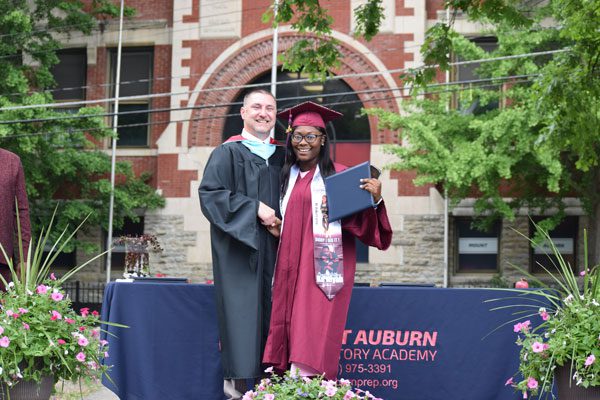 Adult and graduate smiling in academic regalia.