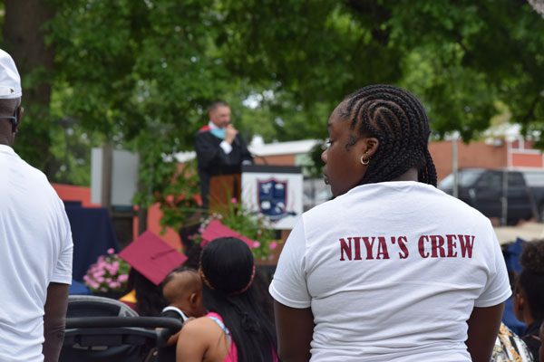 Audience members watch an outdoor graduation ceremony.