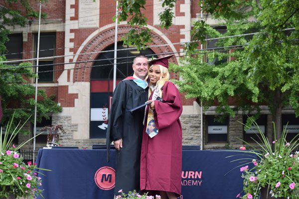 Two adults in graduation attire smiling for a photo.