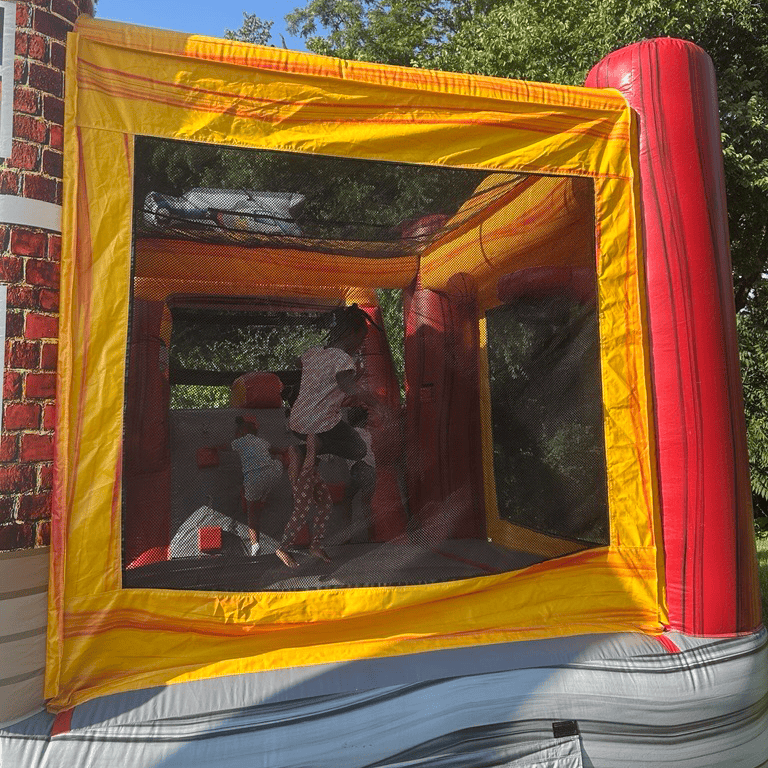 Children playing inside a red and yellow inflatable bounce house.
