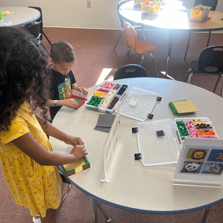 Two children building with colorful interlocking plastic blocks at a table.