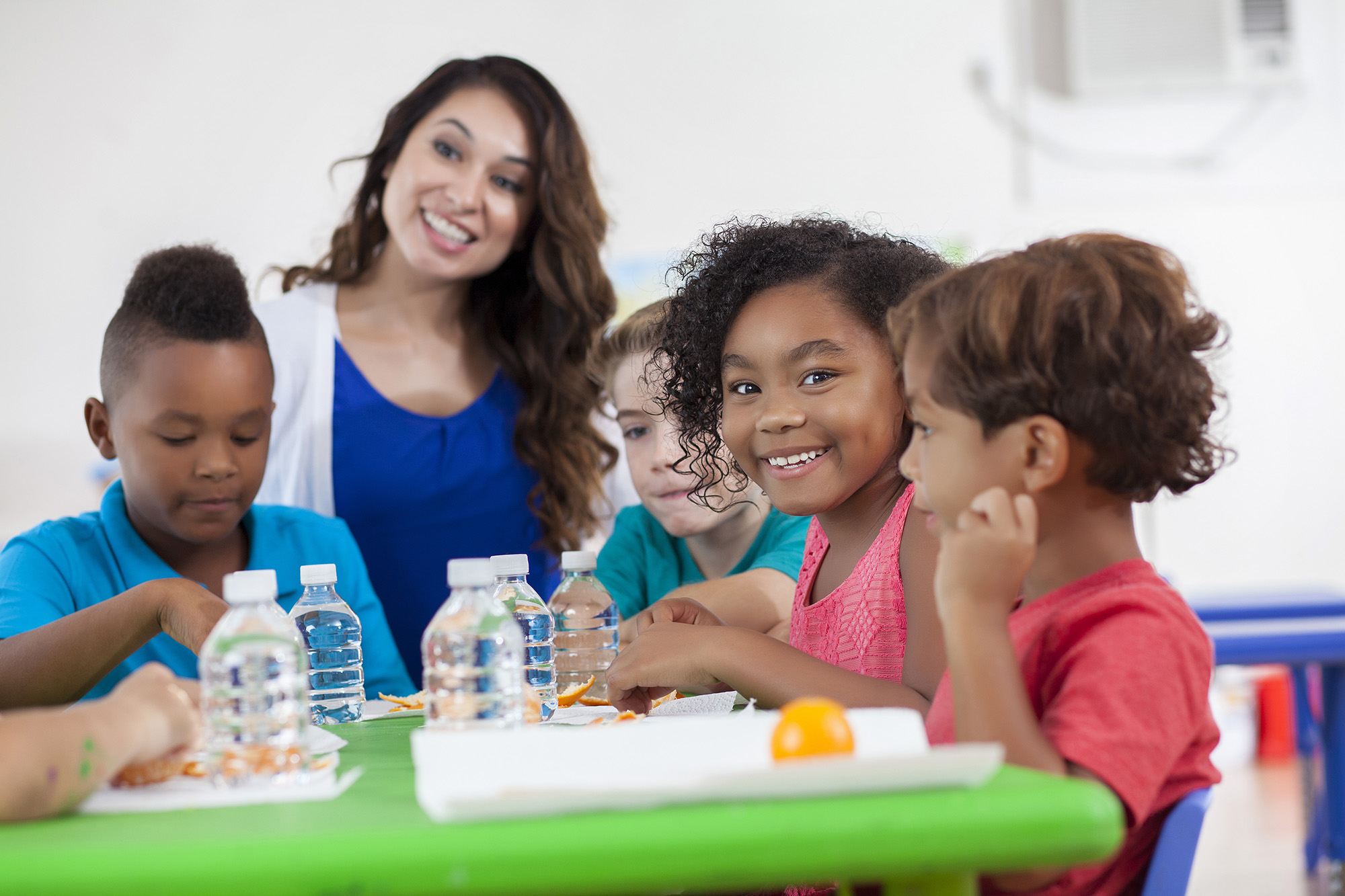 Adult and children at a table with water bottles and orange peels.