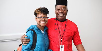 Adult and child smiling, arm around shoulder.