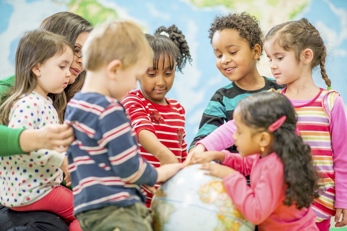 Adult and children gathered around a globe.