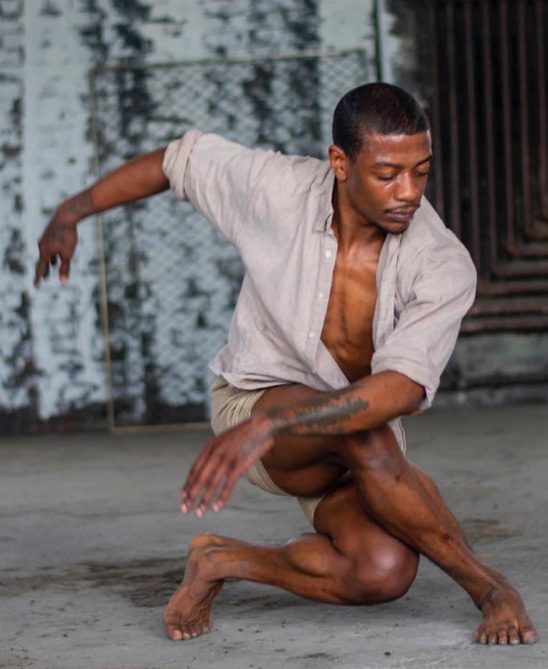 Adult kneeling in a dance pose, looking down.