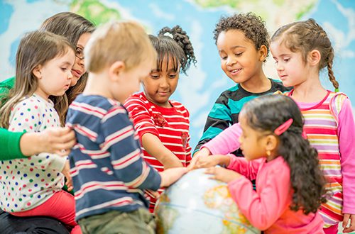 Adult and children looking at a globe.