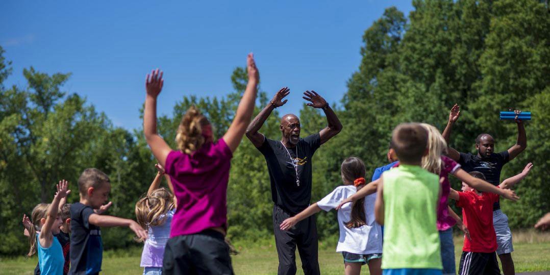 Adults and children raising arms during outdoor exercise.