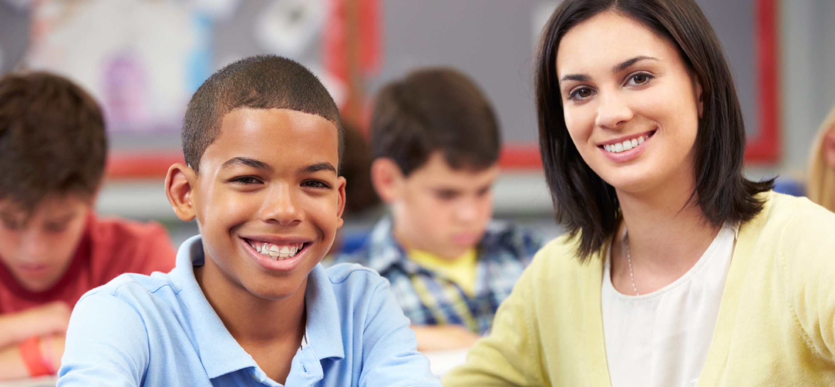 Adult and child smiling in a classroom.