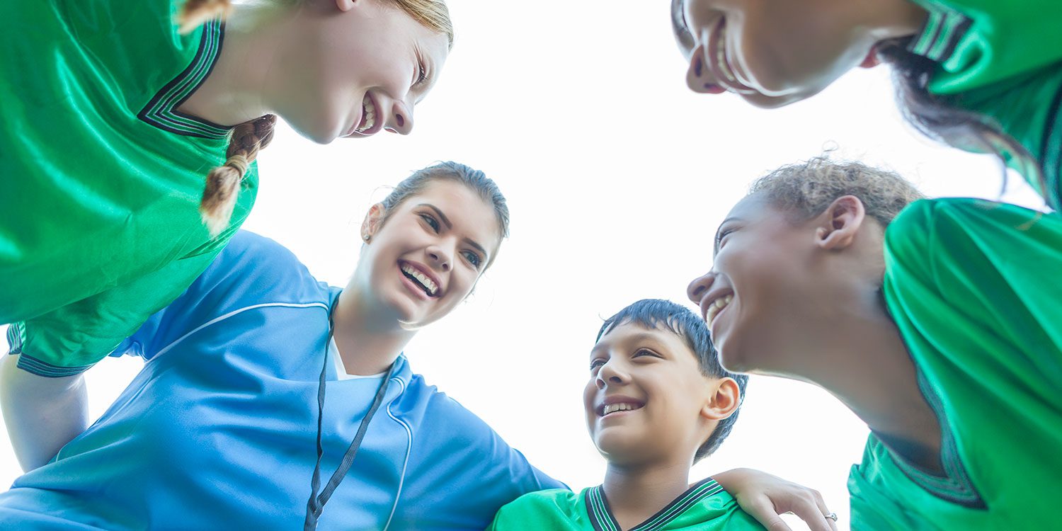 Adults and child smiling in a huddle.