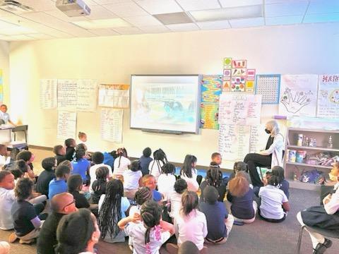 Adult reads to children seated on floor in classroom.