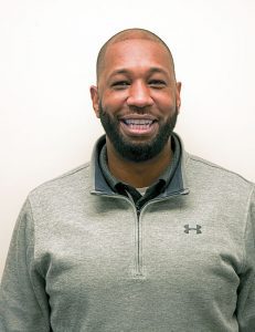 Adult male with beard smiling at camera.