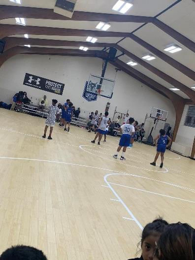 Basketball game with adults and children on a court.