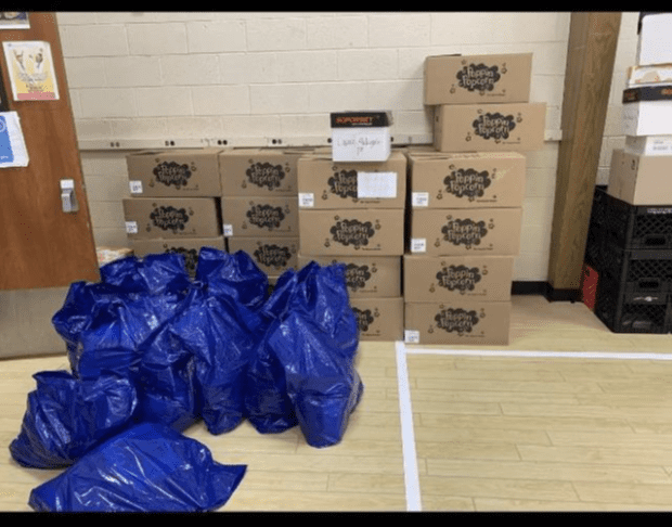 Stacked boxes of popcorn and blue bags on a floor.